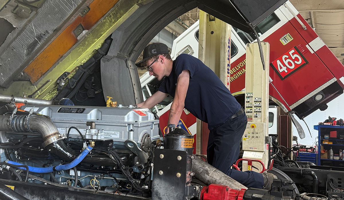 technician working on open hood for truck